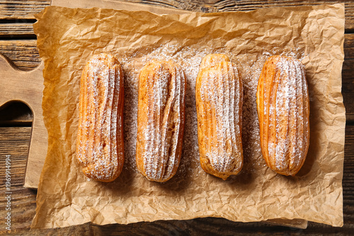 Valokuva Board with tasty eclairs on wooden background
