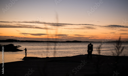 Silhouetted couple kissing by the sea at dusk.