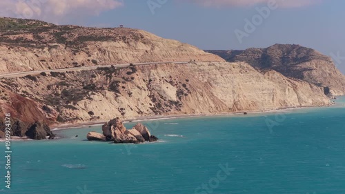 Aerial drone view of a winding coastal road running along steep white cliffs above the turquoise Mediterranean Sea in Cyprus