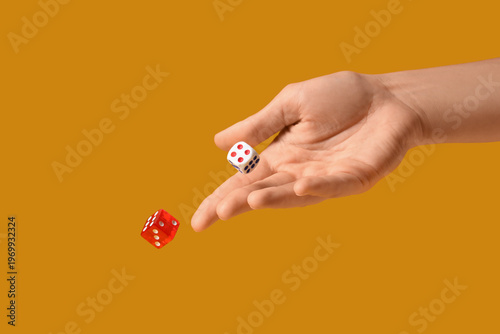 Foto Female hand throwing game dices on orange background