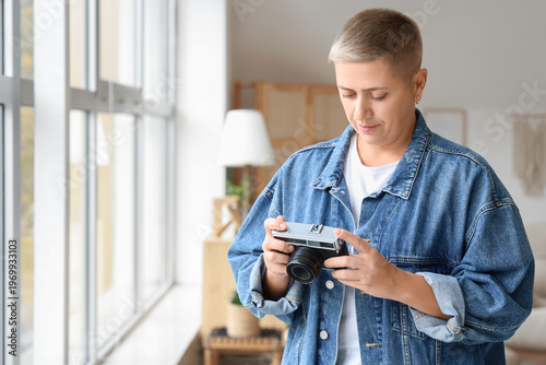 Young woman with short hair and photo camera at home