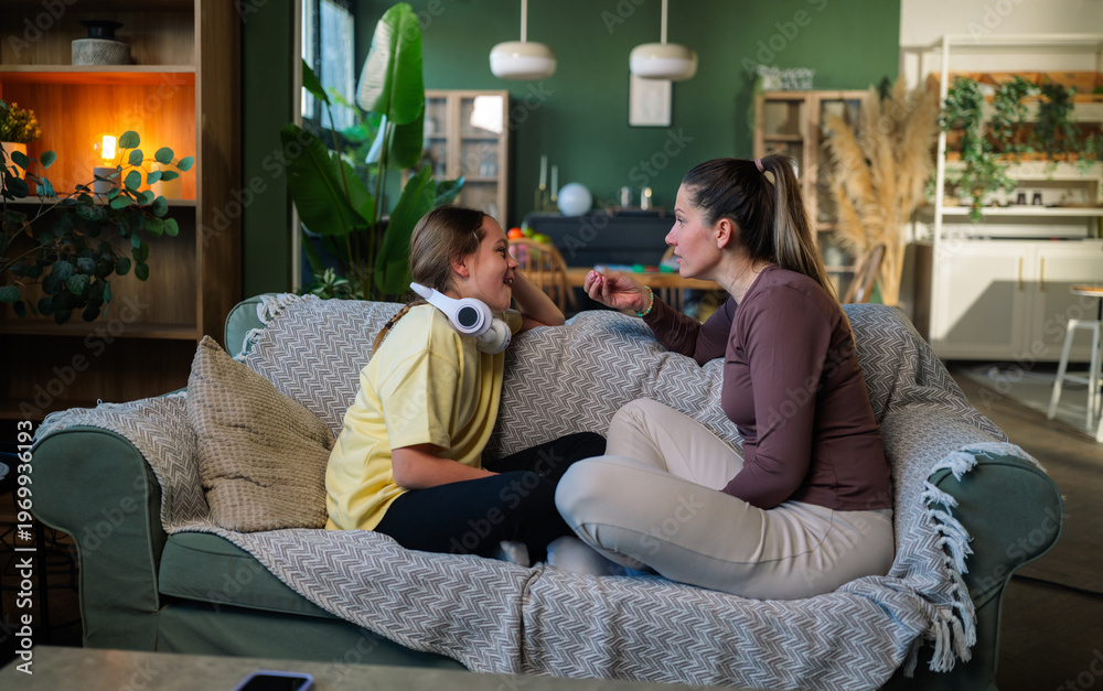 Obraz premium Mother and daughter sitting together on a comfortable sofa in their living room, engaging in a meaningful discussion, fostering a strong bond of trust and open communication