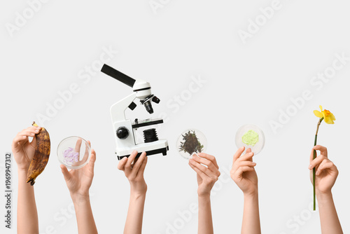 Female hands with modern microscope, daffodil flower, banana peel and Petri d...