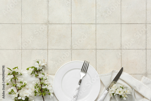 Beautiful table setting with blooming branches on white tile background