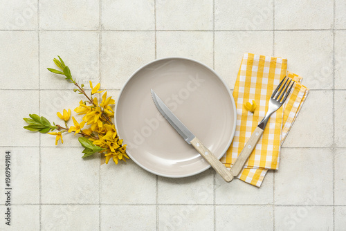 Beautiful table setting with yellow blooming branches on white tile background