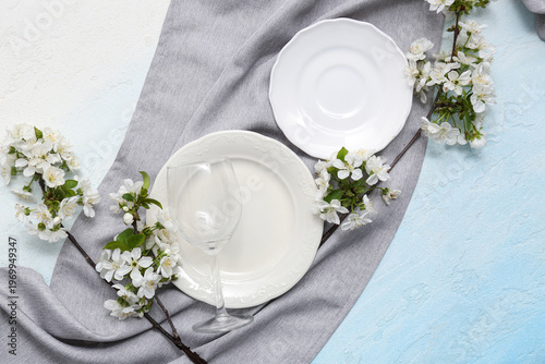Beautiful table setting with blooming branches on light blue background