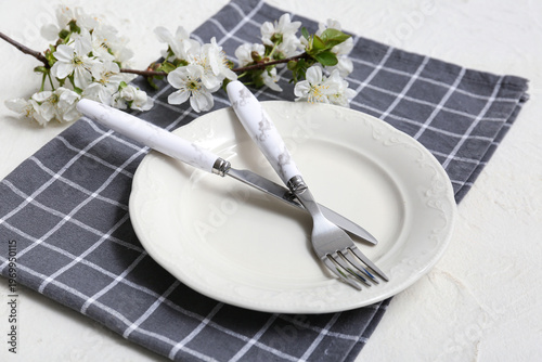 Beautiful table setting with blooming branch on white background, closeup