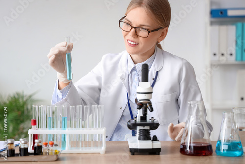 Female scientist with test tube and microscope working in laboratory