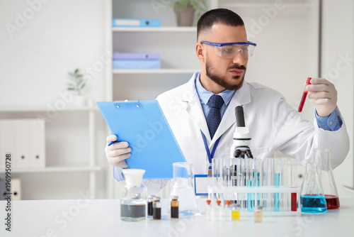 Male scientist with clipboard and test tube working in laboratory