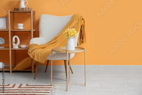 Interior of room with armchair, shelving unit and beautiful daffodils bouquets in vases on table