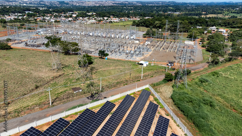 Fotografija A high angle aerial view showing photovoltaic solar panels in the foreground with a large electricity substation and power grid in the background in Atalaia, Goias, Brazil
