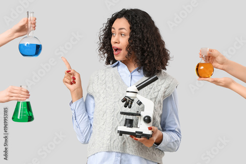 Female African-American teacher holding microscope and hands with flasks on l...
