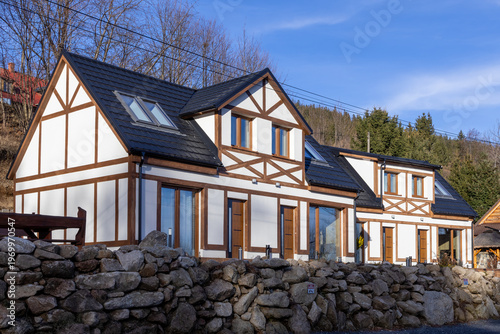 Canvastavla Modern half-timbered houses with white facades and dark roofs, set against a mou
