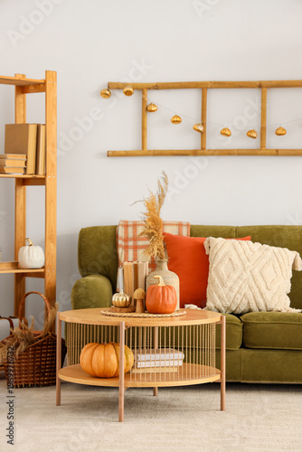 Interior of light living room with autumn decor, sofa and table
