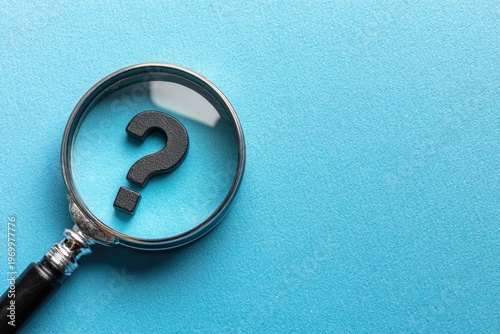 Magnifying glass examining a black question mark on a textured blue surface