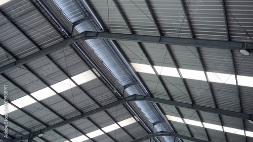 Billede på lærred Close-up of industrial warehouse roof structure with corrugated metal panels, steel beams, and trusses