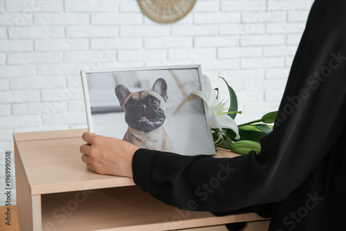 Принти на полотні Person placing framed photo of beloved dog beside white lilies at pet memorial f