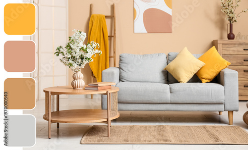 Sofa with dresser, coffee table and vase of white blooming branches near beige wall in living room