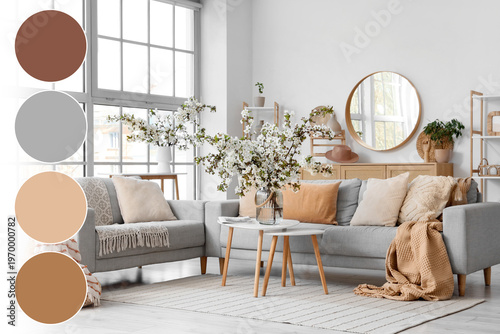 Interior of light living room with sofas and flowering branches in vases
