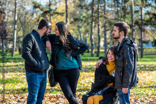 Young woman in a wheelchair with her boyfriend and friends in a park. Two couples