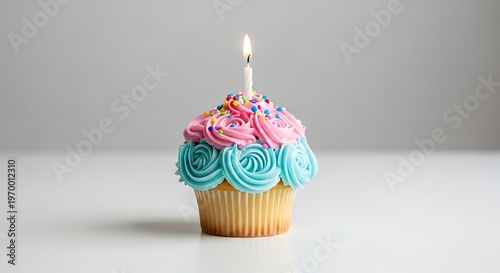 Single Birthday Cupcake with Lit Candle and Colorful Frosting.