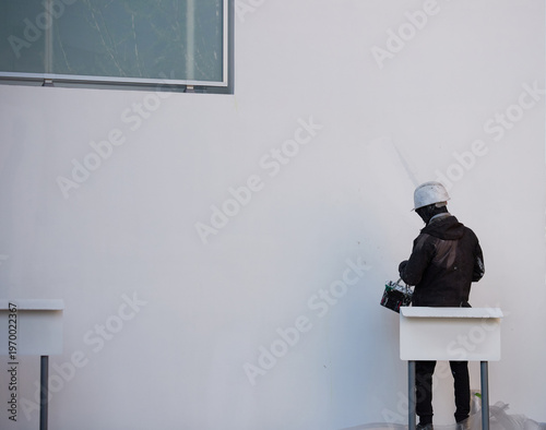 家の外の壁をペンキを塗る男性作業員の姿