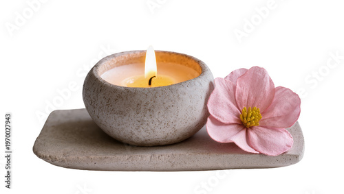 Rustic gray stone candle resting on slate, adorned with delicate pink blossom petals