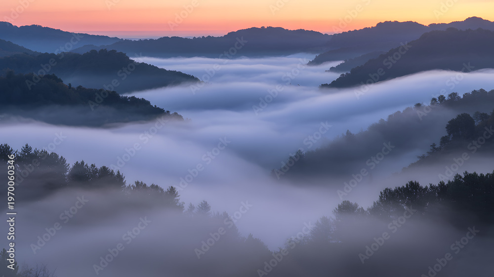 Obraz premium Sunrise over misty valley with rolling hills covered in dense fog