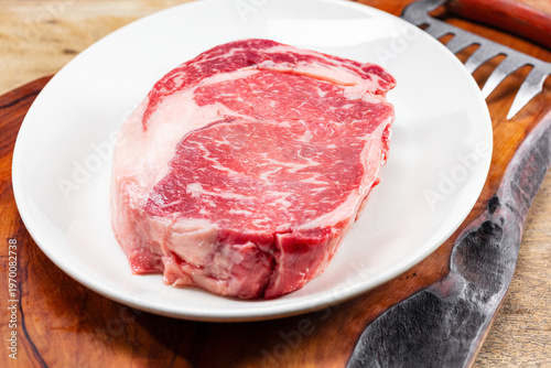Raw beef meat in a plate on a wooden board and wooden table. 