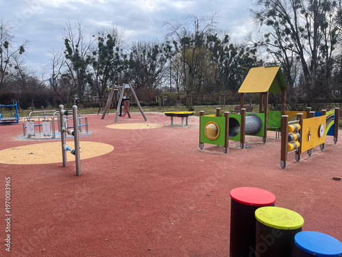 Children enjoy outdoor play at a vibrant playground under a bright, cloudy sky