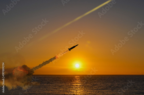 Foto Military missile with smoke trail rises into sky at sunset over sea in conflict