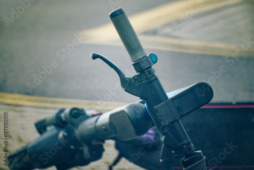Dramatic close-up of an abandoned electric scooter lying on a road. 