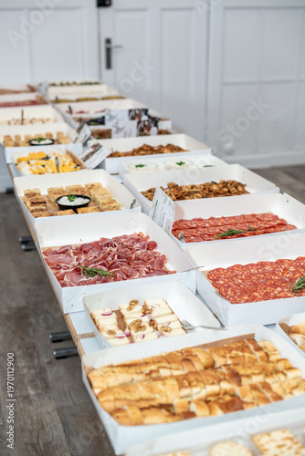 Gourmet Tapas Buffet with Assorted Meat, Cheese, and Bread in White Catering Boxes
