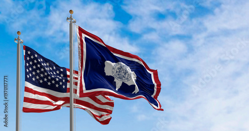 Wyoming state flag and the american flag waving together on a clear day