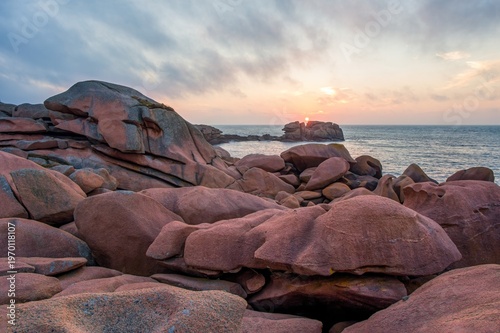 Beautiful sunset over famous pink granite coast in Brittany, France. Unique rock formations along Atlantic ocean create dramatic seascape ideal for travel and nature themes.