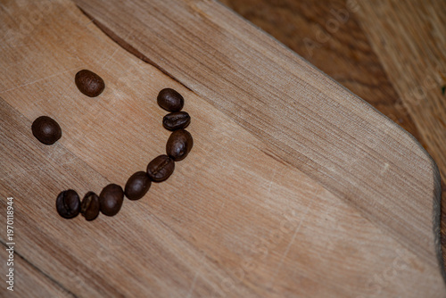 Smiley face made of coffee beans on wooden table