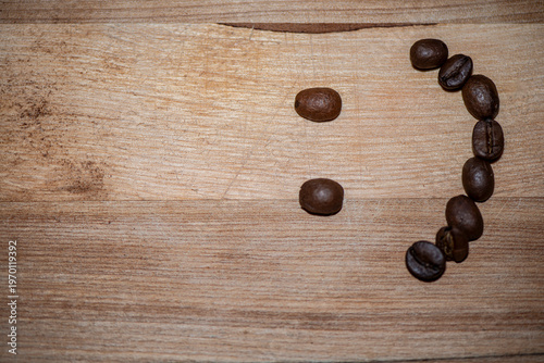Smiley face made of coffee beans on wooden table