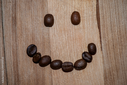 Smiley face made of coffee beans on wooden table
