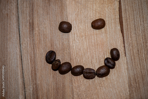 Smiley face made of coffee beans on wooden table