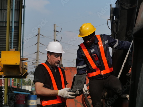 Industrial engineers using rugged laptop for heavy equipment diagnostics in logistics yard