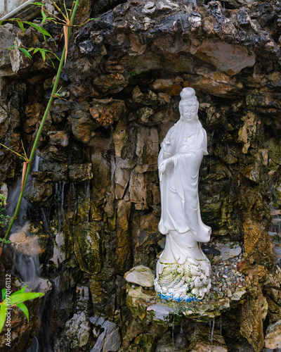 Serene white Guanyin statue amidst a rock waterfall and bamboo at Thean Hou Temple, Kuala Lumpur, Malaysia