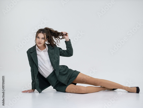 Photography An elegant white woman in business suit talks on a red telephone while sitting on a chair against the backdrop of an isolated space