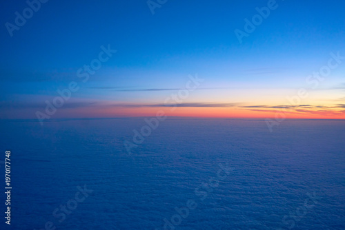 Breathtaking aerial view of a vibrant sunrise over a vast sea of clouds from an airplane window