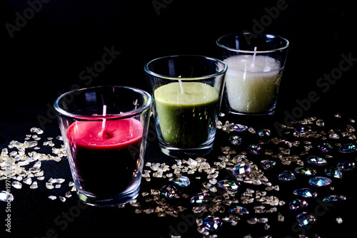 Colorful scented candles in glass holders with decorative crystals on dark background spa and relaxation concept
