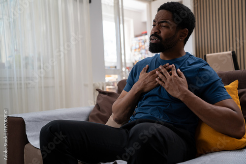 Photos Black man feeling sudden chest pain in the living room