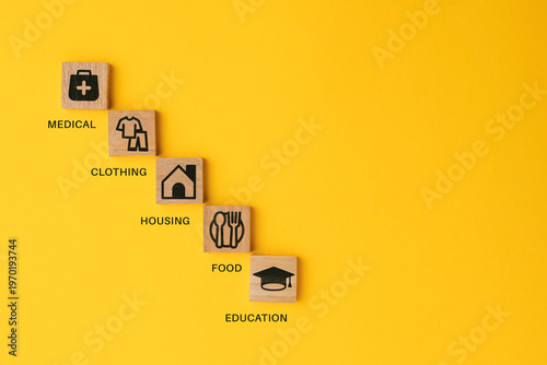 Foto wooden cube with icons of food, Clothing, housing, medical bag, four basic human needs concepts