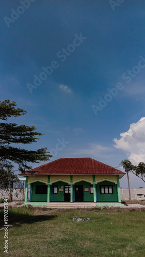 Simple Green Building with Red Roof under Clear Blue Sky.