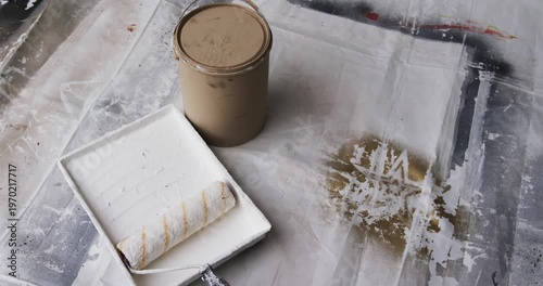 Paint can, tray, roller are resting while camera is panning, revealing stained drop cloth for prep