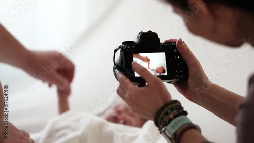 Woman Takes Pictures Of Newborn Baby While Mom Holds Baby Hand. Bright And Warm Setting.