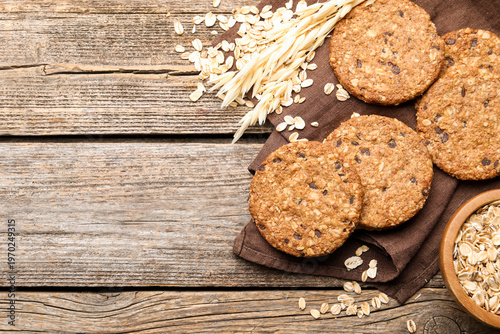 Delicious oatmeal cookies, oat flakes and spikes on wooden table, flat lay. Space for text